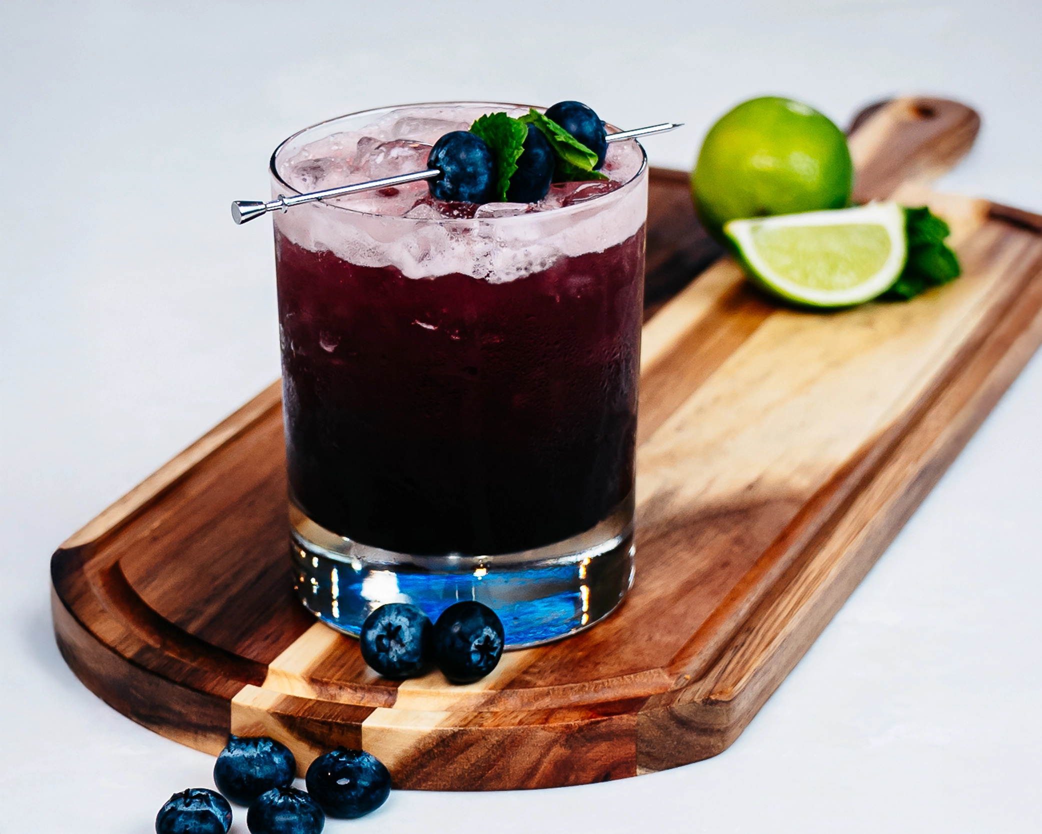 Blueberry lime refresher served over ice in a rocks glass, garnished with blueberries and mint.